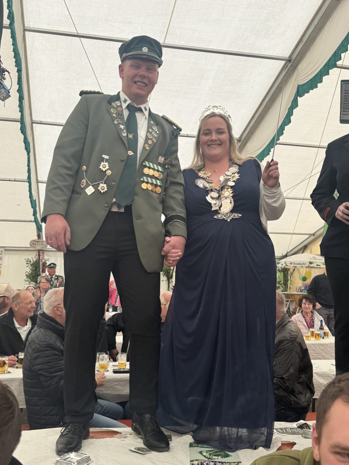 Julia und Pascal stehen Hand in Hand auf einem Biertisch im Festzelt