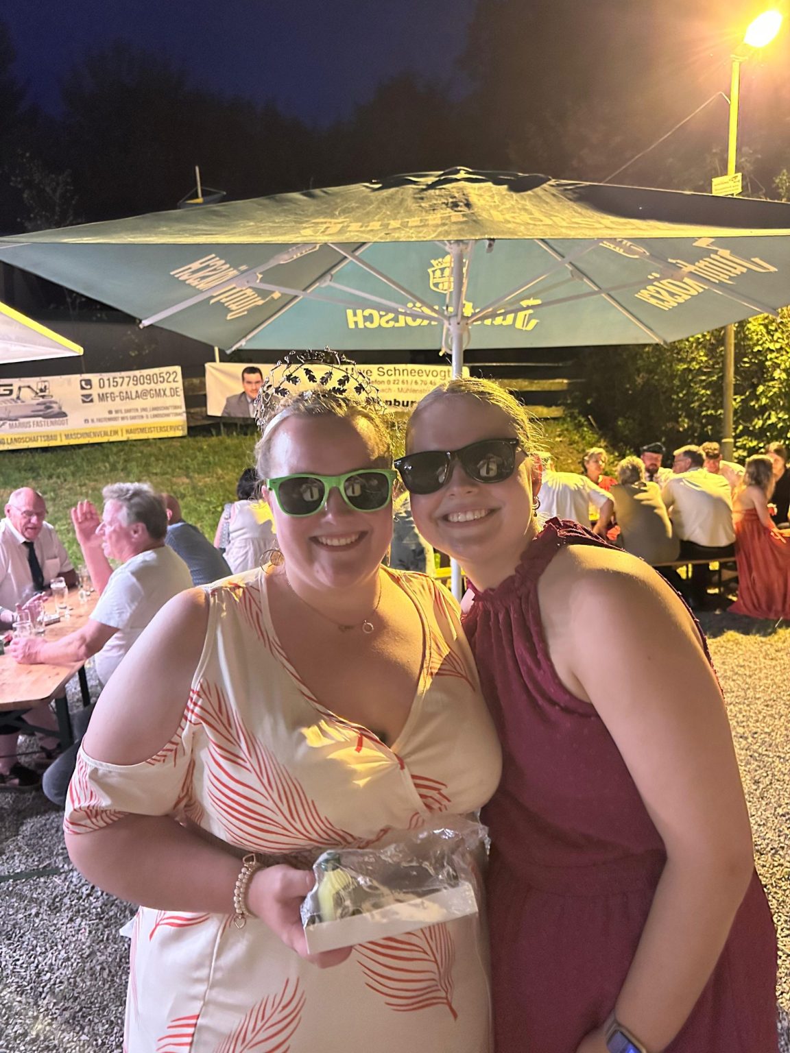 Julia mit grüner Sonnenbrille und Krone bei einem Sommerabend unter dem Sonnenschirm